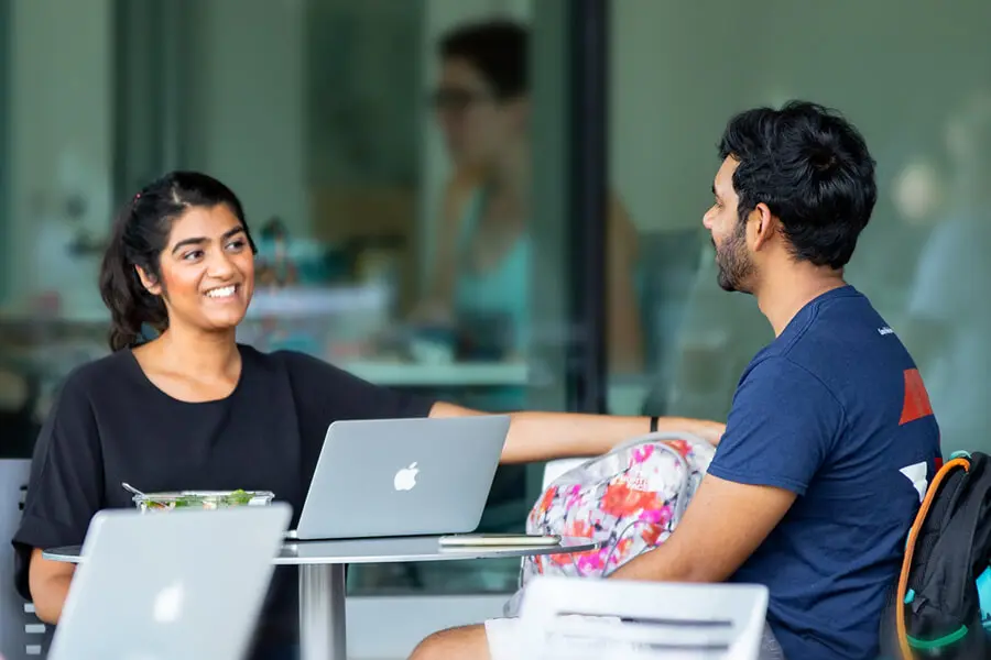 A photo of two students talking on the quad